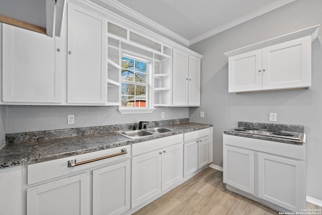 kitchen with light hardwood / wood-style floors, sink, crown molding, white cabinetry, and stovetop