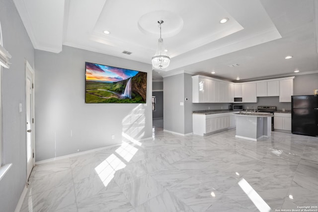 kitchen with a kitchen island, black refrigerator, white cabinetry, ornamental molding, and a tray ceiling