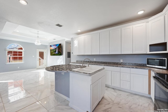 kitchen featuring white cabinets, appliances with stainless steel finishes, sink, hanging light fixtures, and a kitchen island with sink