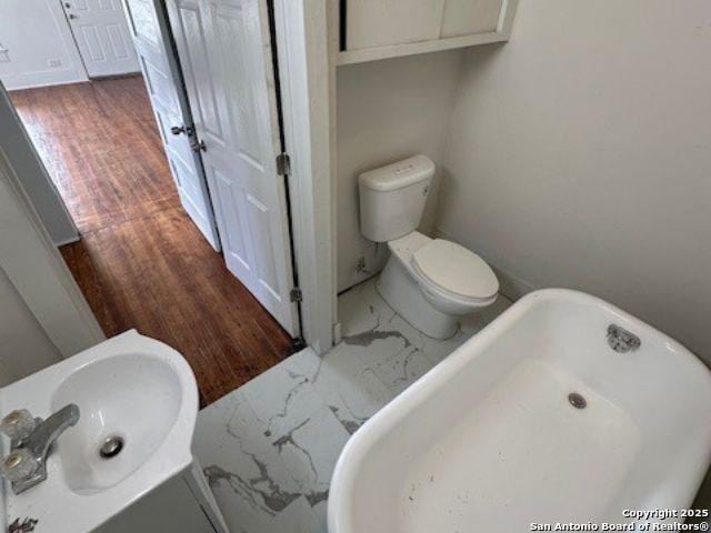 bathroom featuring sink, toilet, and a tub to relax in