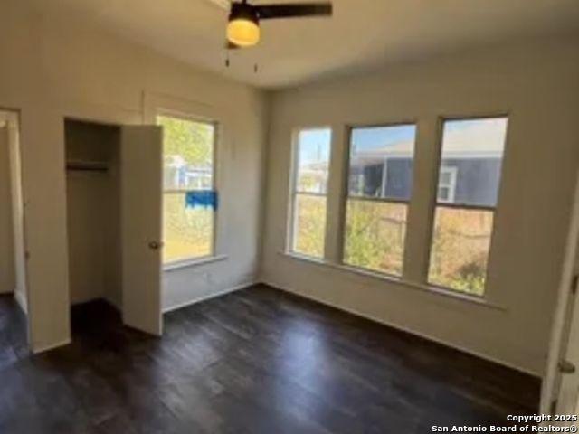 unfurnished bedroom with ceiling fan and dark wood-type flooring