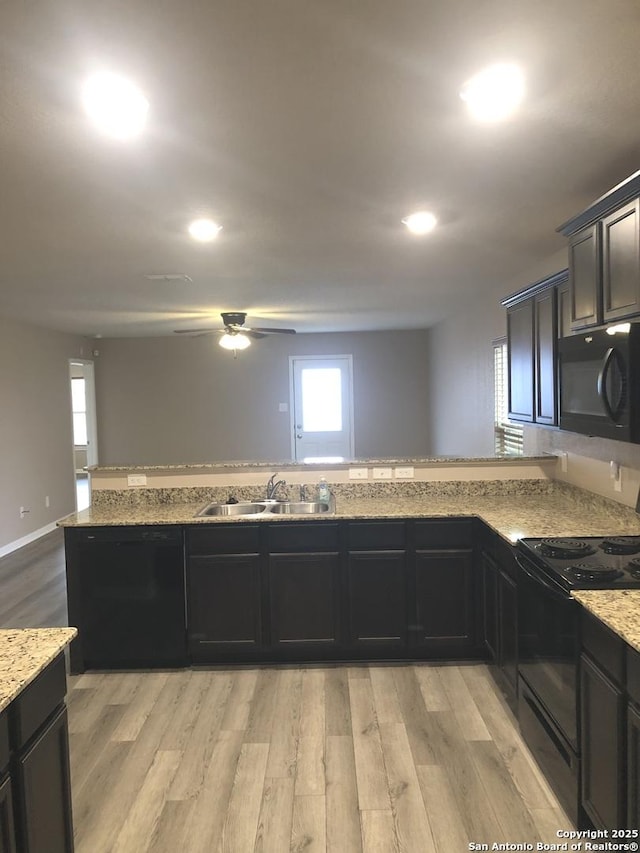 kitchen with light stone countertops, sink, light hardwood / wood-style floors, and black appliances