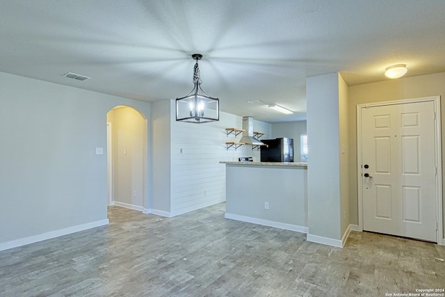 interior space featuring a textured ceiling, an inviting chandelier, and light hardwood / wood-style floors