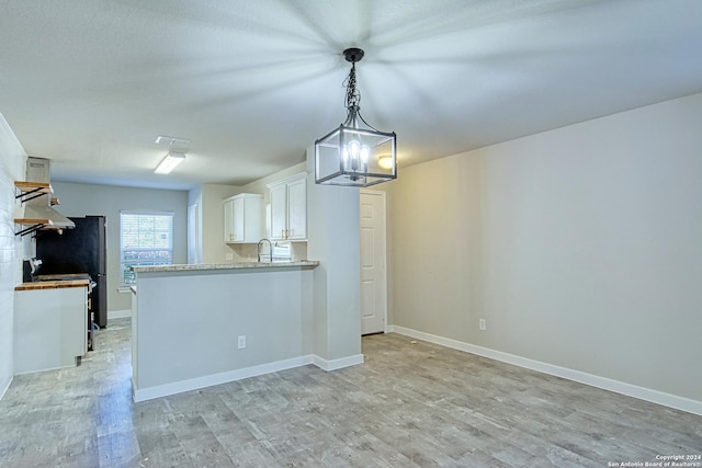 kitchen featuring light hardwood / wood-style floors, kitchen peninsula, decorative light fixtures, white cabinets, and sink