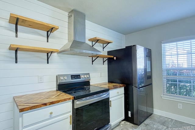 kitchen with white cabinets, appliances with stainless steel finishes, wood counters, island exhaust hood, and wood walls