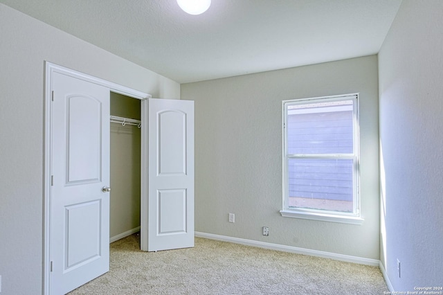 unfurnished bedroom featuring light carpet and a closet