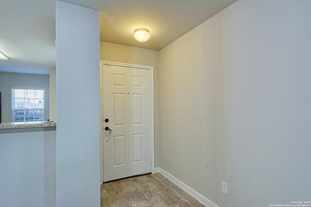 doorway featuring a textured ceiling and light hardwood / wood-style flooring