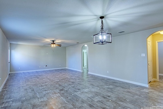 empty room with ceiling fan with notable chandelier and wood-type flooring