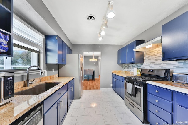 kitchen featuring blue cabinetry, backsplash, appliances with stainless steel finishes, and sink