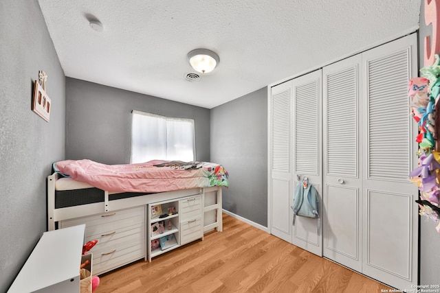 bedroom featuring a textured ceiling, a closet, and light hardwood / wood-style flooring