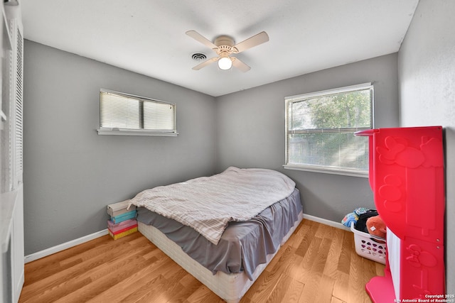 bedroom featuring ceiling fan, multiple windows, and light hardwood / wood-style flooring