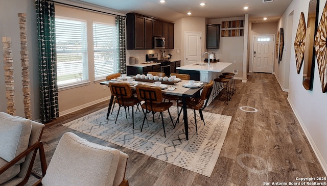 dining room featuring lofted ceiling, sink, a wealth of natural light, and hardwood / wood-style flooring