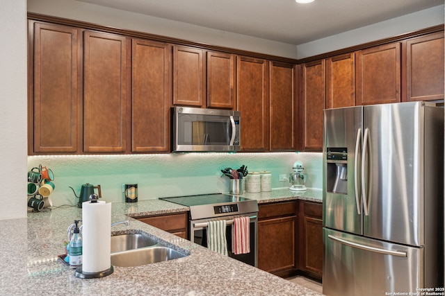 kitchen with appliances with stainless steel finishes, sink, and light stone countertops