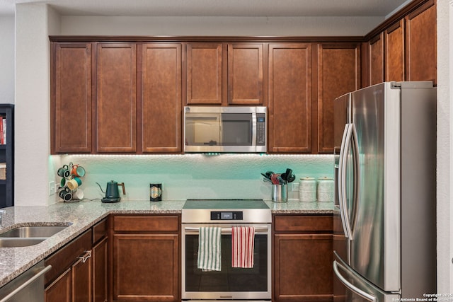 kitchen featuring stainless steel appliances, sink, and light stone countertops