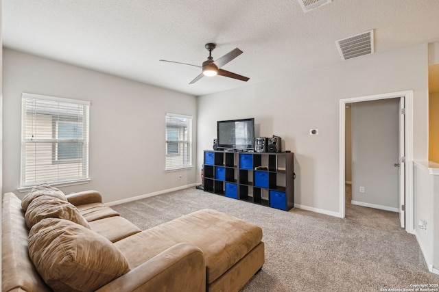 carpeted living room with a textured ceiling, ceiling fan, and a wealth of natural light