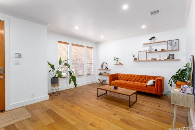 living room with ornamental molding and light hardwood / wood-style flooring