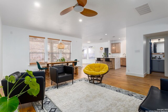 living room with ceiling fan and light hardwood / wood-style flooring