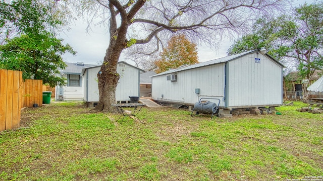 back of property with an AC wall unit, a lawn, and a shed