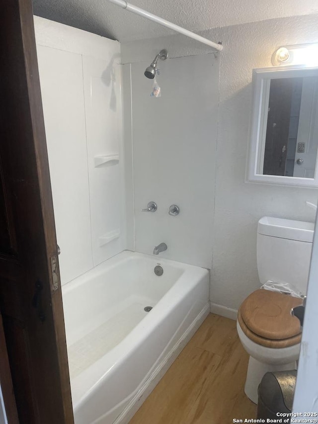 bathroom with toilet, washtub / shower combination, and hardwood / wood-style floors