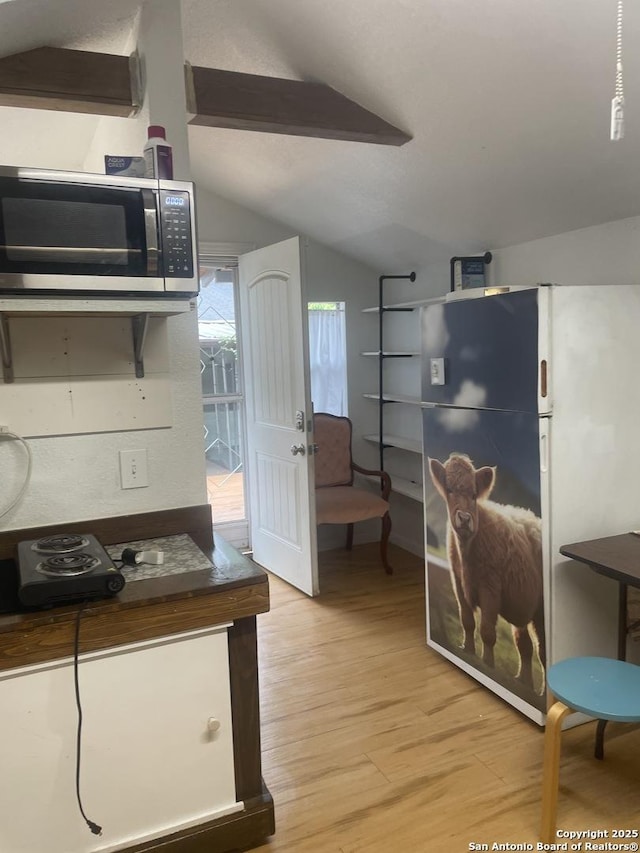 kitchen featuring vaulted ceiling, light hardwood / wood-style floors, and refrigerator