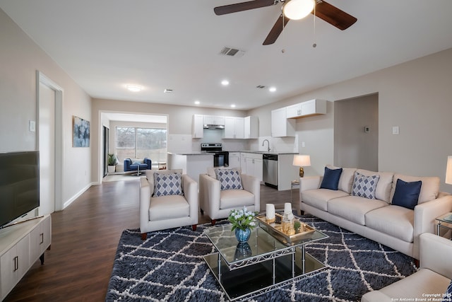 living room featuring ceiling fan, dark hardwood / wood-style floors, and sink