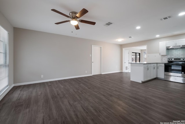 kitchen with electric stove, backsplash, kitchen peninsula, white cabinetry, and dark wood-type flooring