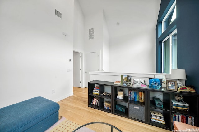 living area with wood-type flooring and a towering ceiling