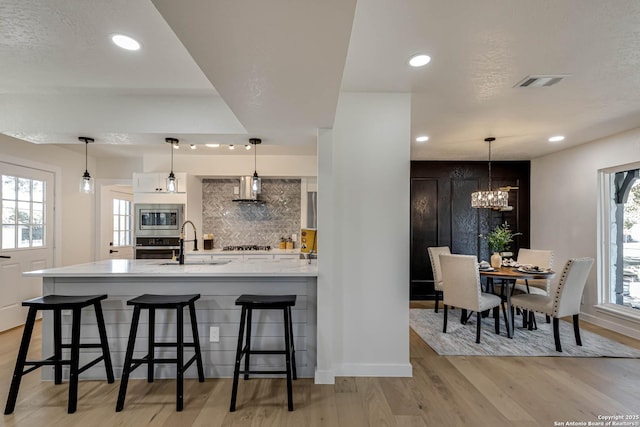 kitchen with appliances with stainless steel finishes, a kitchen bar, hanging light fixtures, and sink