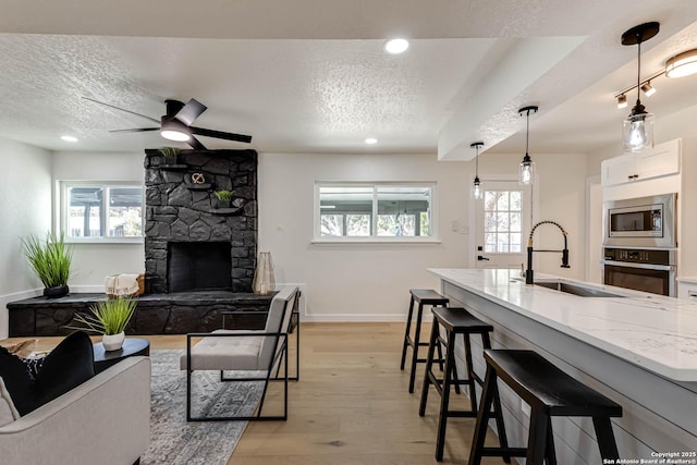 kitchen with decorative light fixtures, a kitchen bar, sink, white cabinetry, and appliances with stainless steel finishes