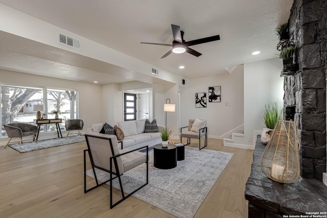 living room with ceiling fan, a textured ceiling, and light hardwood / wood-style flooring