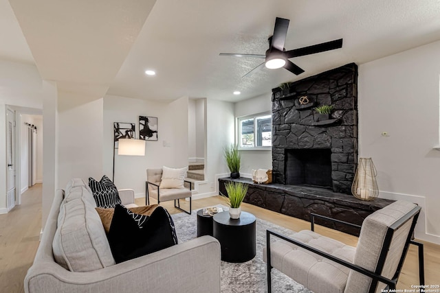 living room featuring ceiling fan, a fireplace, and light hardwood / wood-style flooring