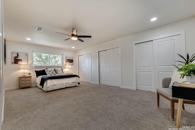 bedroom featuring light carpet, ceiling fan, and multiple closets