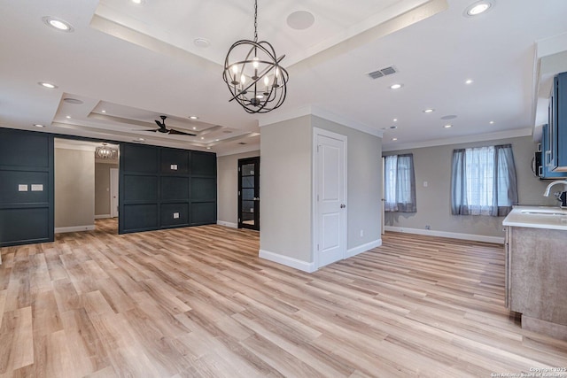 kitchen featuring ceiling fan with notable chandelier, light hardwood / wood-style floors, ornamental molding, and a raised ceiling