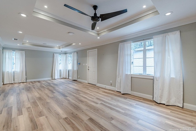 spare room with ceiling fan, crown molding, light hardwood / wood-style floors, and a tray ceiling