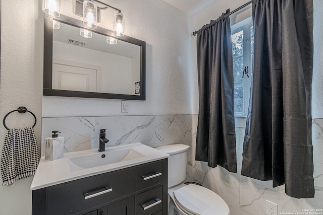 bathroom with tile walls, toilet, and vanity