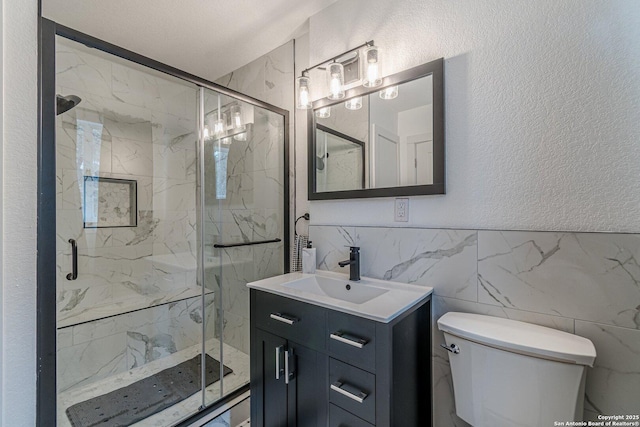 bathroom featuring toilet, tile walls, a shower with door, and vanity