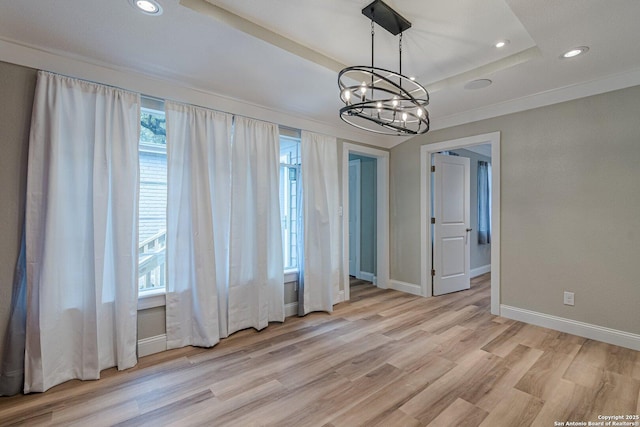 unfurnished dining area featuring plenty of natural light, light hardwood / wood-style flooring, a raised ceiling, and a notable chandelier