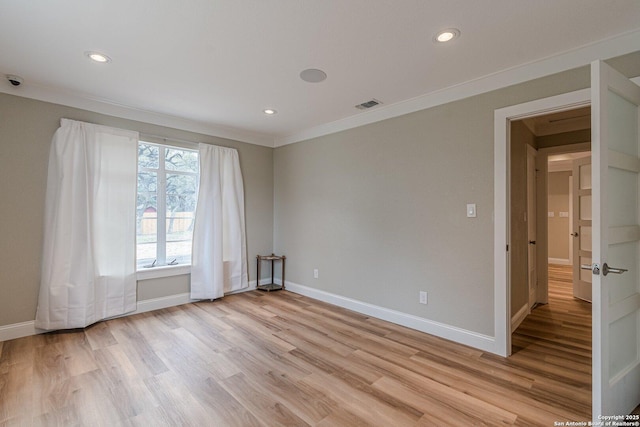 spare room featuring ornamental molding and light hardwood / wood-style flooring