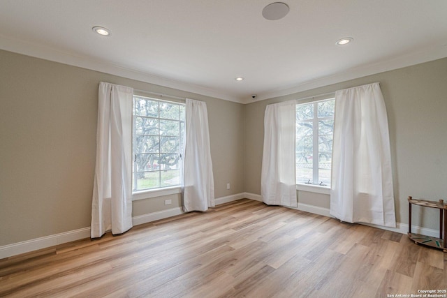 empty room featuring light hardwood / wood-style floors, crown molding, and a healthy amount of sunlight