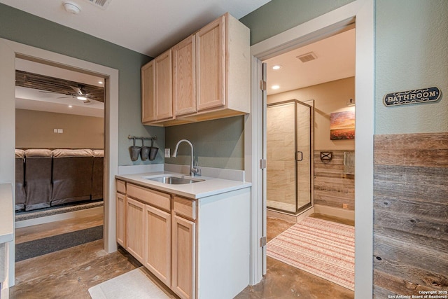 kitchen with ceiling fan, light brown cabinetry, sink, and concrete floors