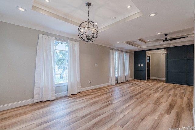 spare room featuring ceiling fan with notable chandelier, a tray ceiling, ornamental molding, and light hardwood / wood-style floors