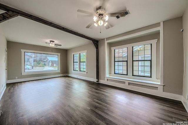 spare room with a ceiling fan, visible vents, baseboards, and dark wood-style floors