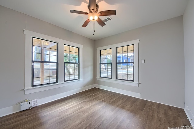 empty room with a ceiling fan, visible vents, baseboards, and dark wood-style flooring