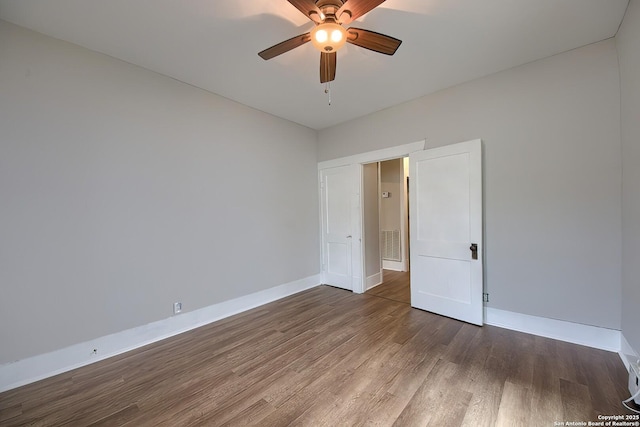 unfurnished bedroom featuring dark wood-type flooring, a ceiling fan, and baseboards