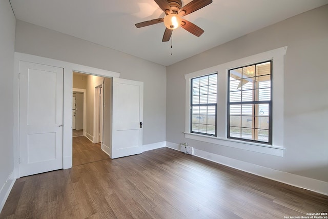 unfurnished bedroom featuring dark wood-type flooring, baseboards, and a ceiling fan