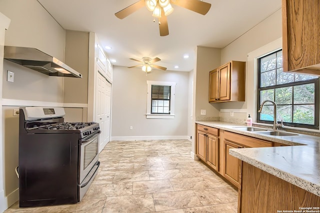 kitchen featuring stainless steel gas range, a healthy amount of sunlight, brown cabinetry, and a sink