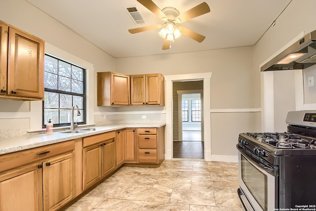 kitchen with visible vents, a ceiling fan, stainless steel range with gas stovetop, range hood, and a sink