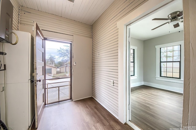 entryway with wood walls, ceiling fan, a wealth of natural light, and wood finished floors