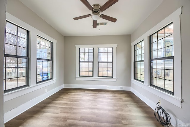 empty room featuring baseboards, visible vents, ceiling fan, and wood finished floors