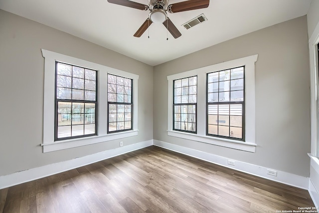 unfurnished room featuring visible vents, ceiling fan, baseboards, and wood finished floors